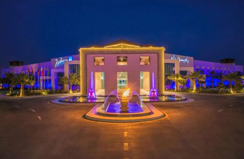 半月湾Radisson Blu Resort, Al Khobar Half Moon Bay的一座建筑,在晚上前方有一个喷泉