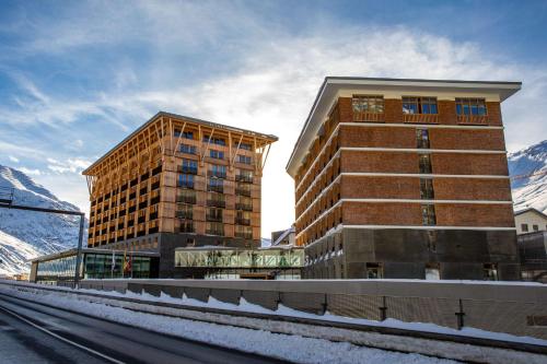 安德马特Radisson Blu Hotel Reussen, Andermatt的一座高大的建筑,旁边是一座白雪 ⁇ 的山