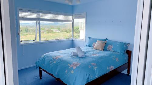罗托鲁瓦Panoramic View Apartment Without a Kitchen的蓝色卧室,配有一张带窗户的床