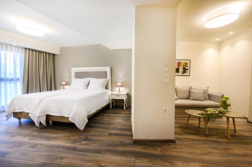 弗洛里纳Emerald Suites的卧室配有一张白色的大床和一张沙发。