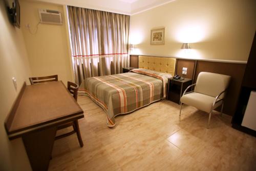 圣保罗索内卡广场酒店的一间卧室配有一张床、一张桌子和一把椅子