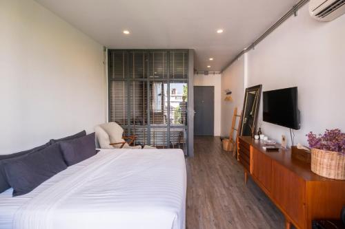 清迈Iron32 Hotel的卧室配有白色的床和电视。