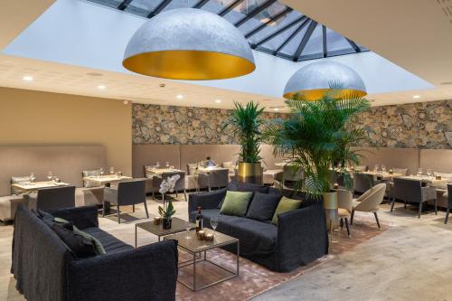 圣布里厄Edgar Hôtel & Spa - Table Gastronomique的一间带桌子、沙发和桌面的用餐室