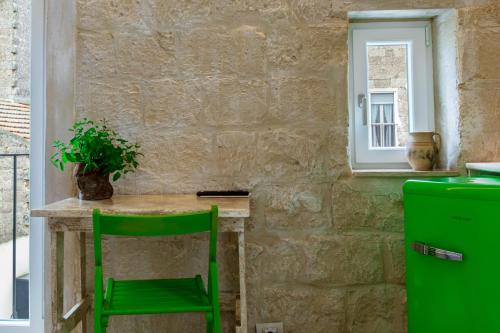 阿尔塔穆拉B&B PIAZZA SAN GIOVANNI - ESSENZE DELLA MURGIA的厨房里一张小桌子上摆放着绿椅