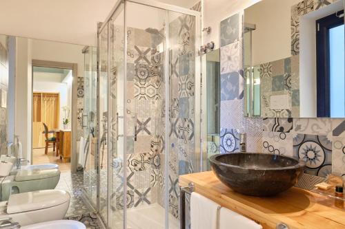 阿格罗波利La Via del Porto Charme Rooms的浴室设有玻璃淋浴间和黑碗