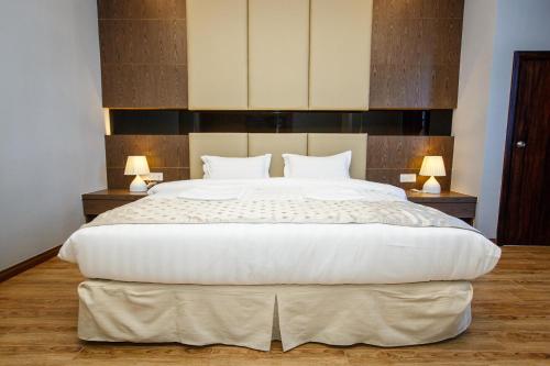 哥打京那巴鲁Lintas Platinum Hotel的一张大白床,位于带两盏灯的房间