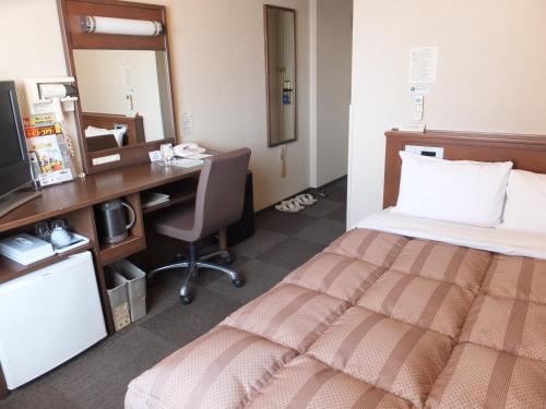 大仙市大曲站前路线酒店的酒店客房配有一张床、一张书桌和一台电脑