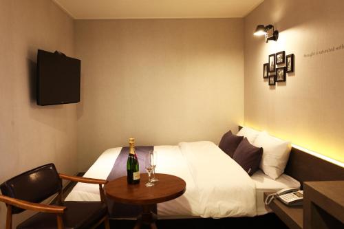 大田S& Hotel的酒店客房,配有一张床和一张桌子,并提供一瓶香槟