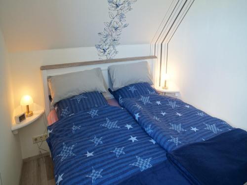 TaarstedtFerienwohnung an der Au的一张带蓝色棉被的床和两个枕头