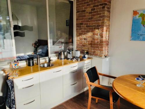 鹿特丹义曼哥尼住宿加早餐旅馆的厨房配有白色橱柜、桌子和砖墙