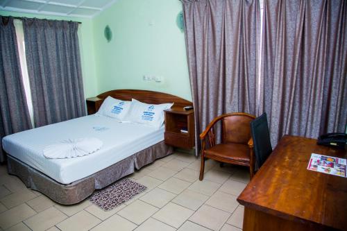 布拉柴维尔Résidence Hôtelière de Moungali的一间卧室配有一张床、一张桌子和一把椅子