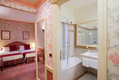 米兰Hotel Milano Regency的一间卧室配有一张床、一个浴缸和一个水槽