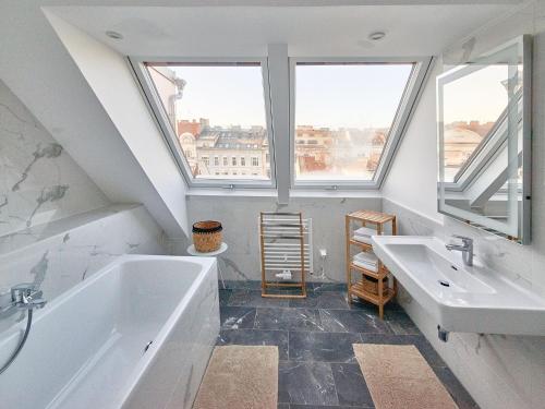 维也纳普利马维拉2号酒店的一间带两个盥洗盆和浴缸的浴室以及窗户。