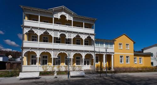 奥斯赛拜-塞林Haus Sonne的黄色和白色的建筑,前面有长凳