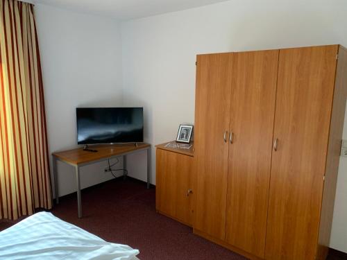 基尔恩Pension Hannes的一间卧室配有一张桌子、一台电视和一个木制橱柜