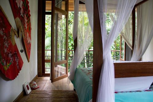 坎布里Estalagem Camburi的一间卧室设有一张天蓬床和一个阳台