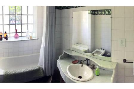 圣伊西德罗Habitación en casa con gran jardín的一间带水槽、浴缸和镜子的浴室