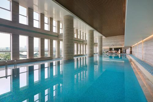 无锡无锡新湖铂尔曼大酒店的大楼内的一个蓝色海水游泳池