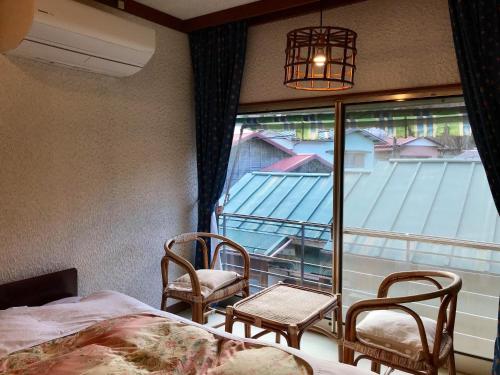 箱根月乃屋酒店的一间卧室配有一张床、两把椅子和一个窗户