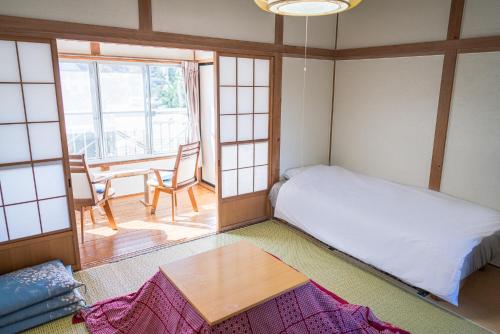 富士河口湖Ryokan Fuji Heights的小房间设有一张床和一张桌子