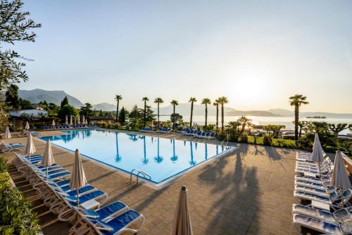 马内尔巴Onda Blu Resort的一个带躺椅的大型游泳池,棕榈树