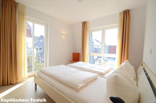 诺德奈Kapitänshaus Tordalk mit 3 Schlafzimmern的一间卧室设有两张床和大窗户