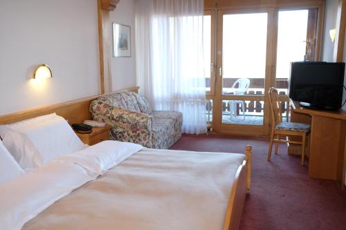 Visperterminen红峰酒店及餐馆的酒店客房配有一张床、一把椅子和一台电视。