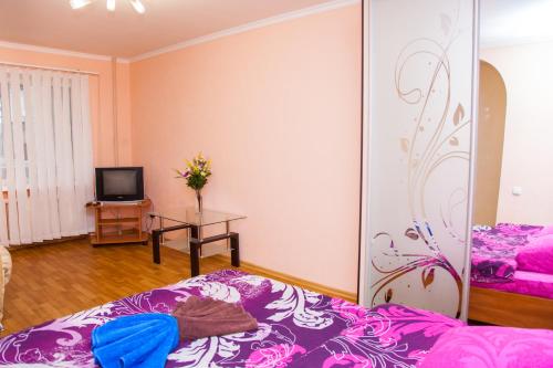 扎波罗热Semi-luxury Apt on Nezalezhnoi Ukrаiny 63 near Intourist Hotel的客房设有一张带紫色床单的床和一台电视。