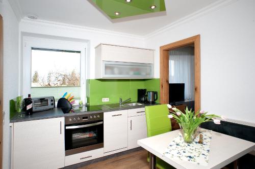 OberaichwaldGästehaus Elisabeth的厨房配有白色橱柜和绿色墙壁