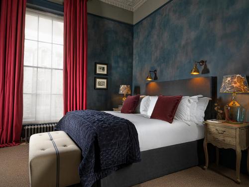 切尔滕纳姆海滨长廊131号酒店的一间卧室配有一张带红色窗帘的大床