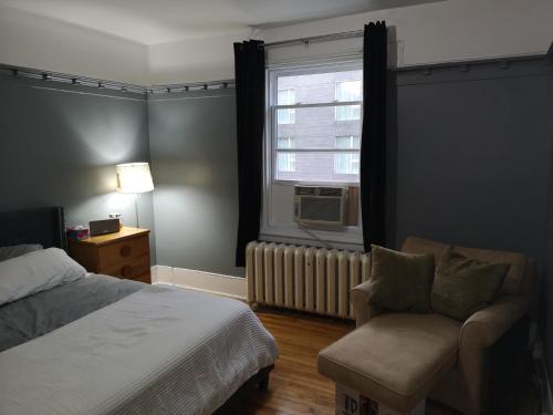 蒙特利尔Room with King Bed in Shared 3 Bedroom Downtown的卧室配有床、椅子和窗户。