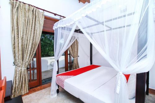 本托塔Chami Villa Bentota的窗户客房内的一张带天蓬的床