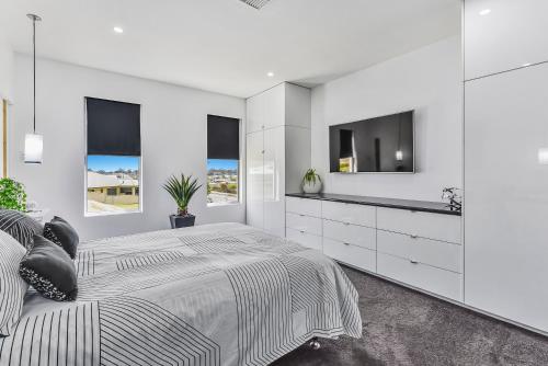 芒特甘比尔CONROE EXECUTIVE TOWNHOUSE - MODERN & STYLISH的白色卧室设有一张大床和一台平面电视。