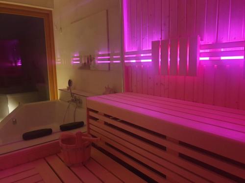 岑平Ferienhaus Inselliebe mit Sauna的带浴缸和粉红色灯的浴室。
