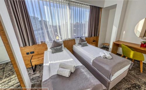 萨拉热窝Orange Hotel的酒店客房设有两张床、一张书桌和一个窗户。