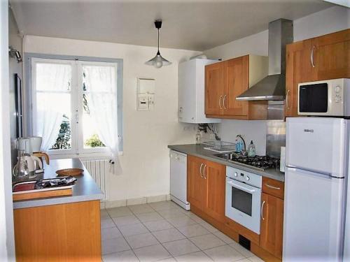 基伯龙Ty Lisa - Spacieuse maison de village paisible proche ville et plages - 5 chambres - Kermorvan的厨房配有木制橱柜和白色冰箱。