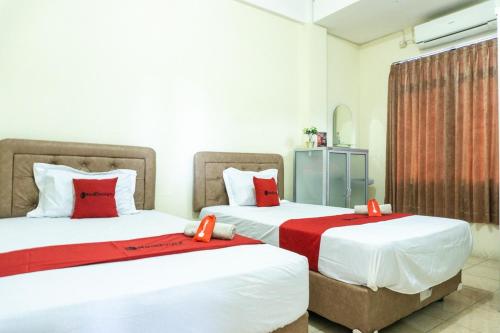 英德RedDoorz @ Gatot Subroto Ende的两张位于酒店客房的床铺,配有红色枕头