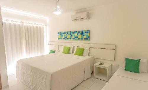 塞古罗港FLAT RESID MONT CARMELO的白色卧室配有一张带绿色枕头的大床