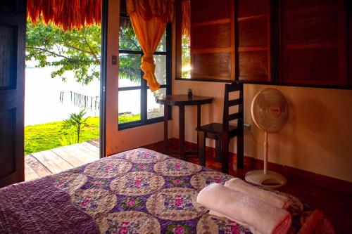 弗洛勒斯Mayan Spirit的一间卧室设有一张床、一个窗口和风扇