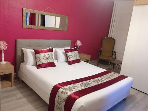 BonsonHOTEL HOSTELLERIE DES VOYAGEURS的卧室配有一张带粉红色墙壁的大床