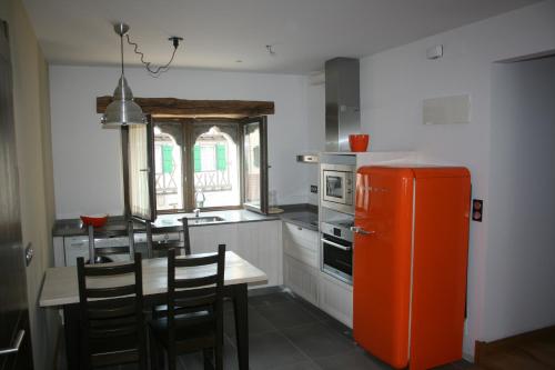 莱萨卡古尔伊多陪公寓的厨房配有橙色冰箱和桌椅