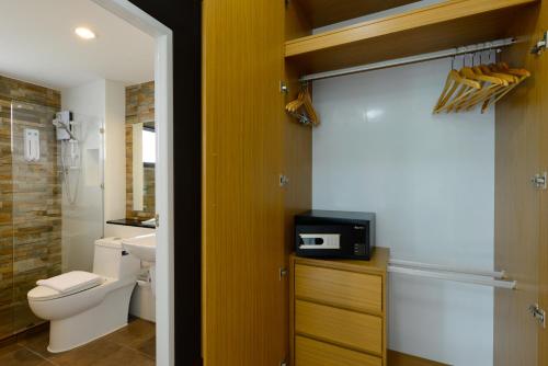 曼谷曼谷斯瑞拉哈达酒店的一间带卫生间的浴室和一台位于柜台上的电视