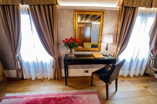 威尼斯EGO' Residence Venice的一张带镜子和红花瓶的桌子