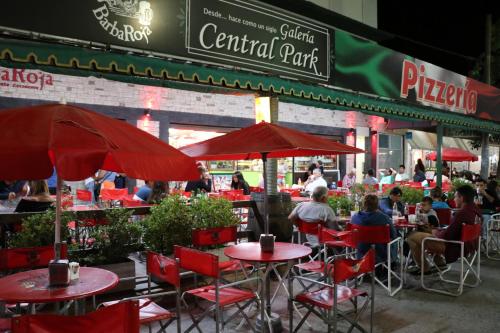 圣克拉拉德尔马尔Hotel Central park的一间设有红色桌椅的餐厅,以及坐在餐厅里的人