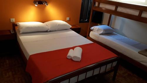 波萨达斯Hotel Vanderloo的配有两张带两张白色拖鞋的床铺的客房