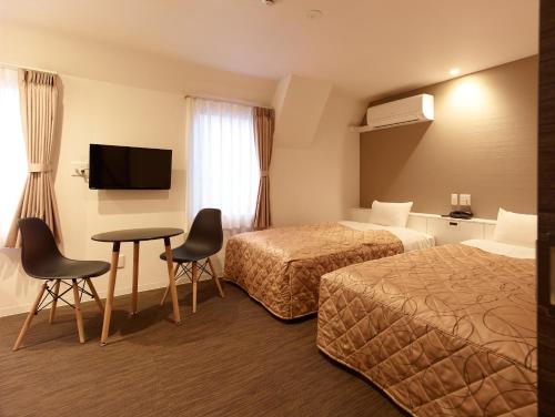 东京新东北酒店的酒店客房带两张床和一张桌子以及椅子。