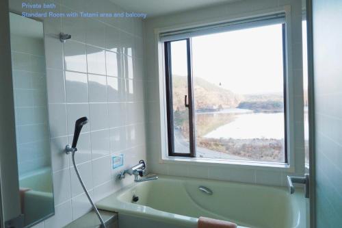 富士河口湖松杰山酒店的带浴缸的浴室和窗户。