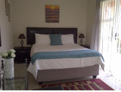 约翰内斯堡SunSet West Self Catering Maraisburg Roodepoort的一间卧室设有一张大床和一个窗户。
