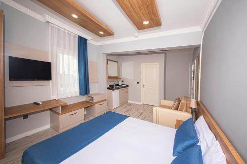 博德鲁姆Marina Hotel Bodrum的一间卧室配有一张床、一张书桌和一台电视。