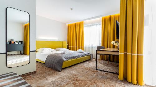 克拉科夫Qubus酒店的一间卧室配有黄色窗帘、一张床和镜子